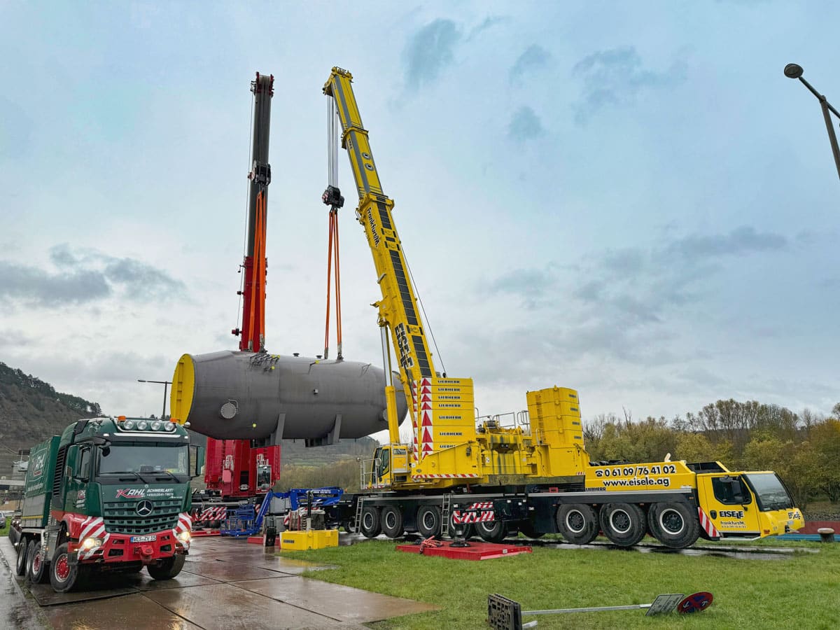 Heat exchanger discharge onto a truck–trailer configuration of 16-axle modular trailers by two mobile cranes at the Lengfurt private jetty Heat exchanger discharge onto a truck–trailer configuration of 16-axle modular trailers by two mobile cranes at the Lengfurt private jetty
